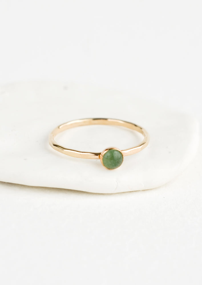 Thin gold ring with bezel set green stone.