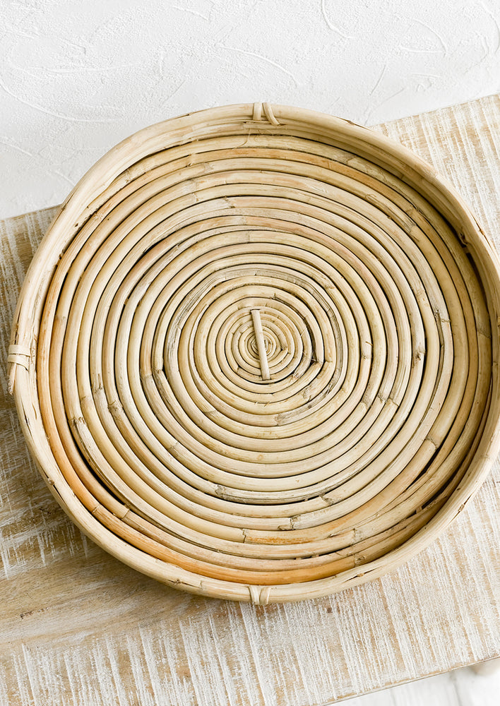 1: A round, shallow woven tray made from rattan.