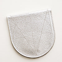 Metallic Silver: A metallic silver leather half-oval wallet with a subtle geometric pattern.
