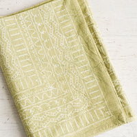 1: A folded green tablecloth with a white geometric print.