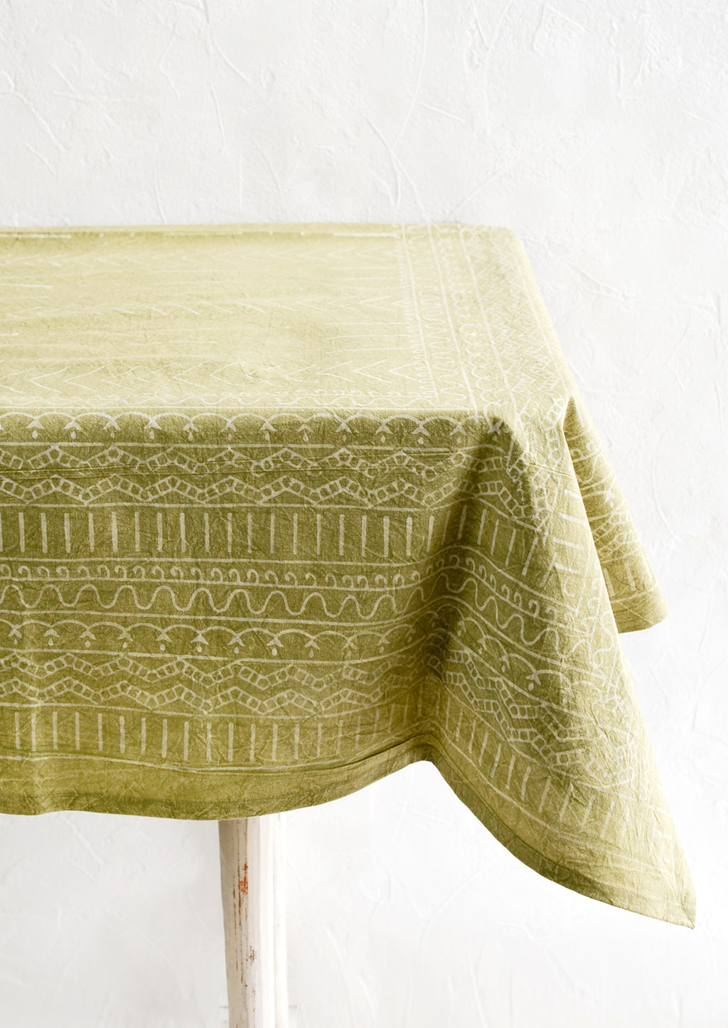 2: A green tablecloth with a white geometric print spread out over a table.
