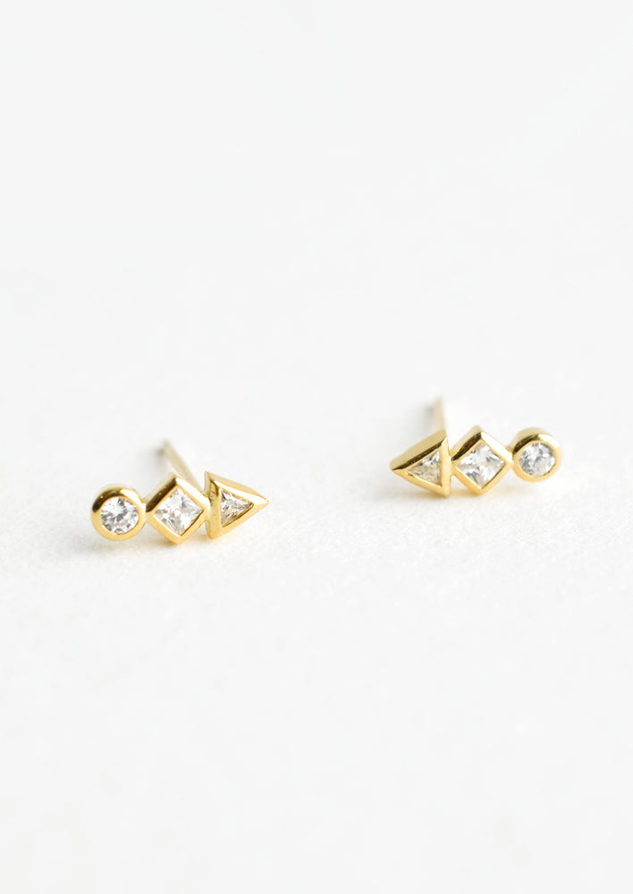 2: A pair of gold stud earrings with a circle, diamond and triangle crystal stacked in a row.