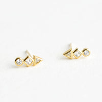 2: A pair of gold stud earrings with a circle, diamond and triangle crystal stacked in a row.