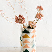2: A sweetgrass vase woven in triangle print with dried pink flowers inside.