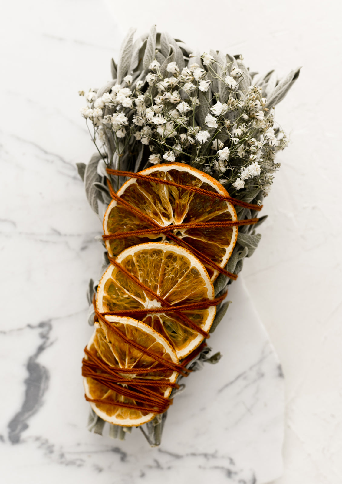 An extra large smudge bundle with sage, white flowers and dried oranges.