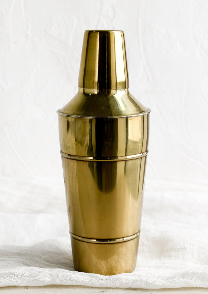 A metal cocktail shaker with gold finish.