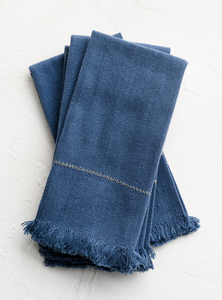 A set of four blue napkins with fine gold stitching.