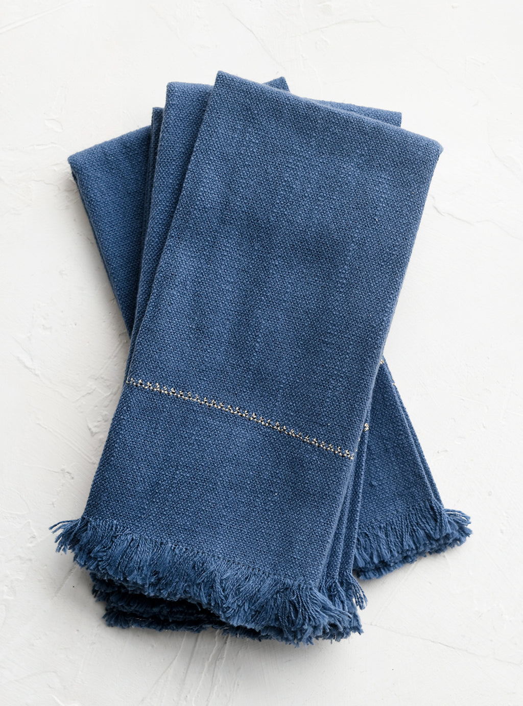 1: A set of four blue napkins with fine gold stitching.