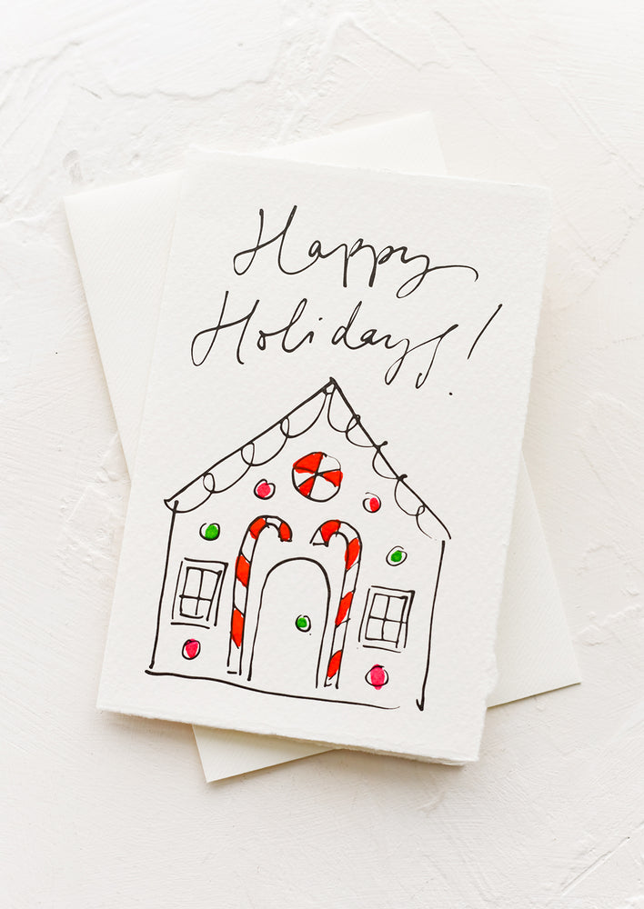 A greeting card with illustration of gingerbread house, text reads "Happy holidays!".