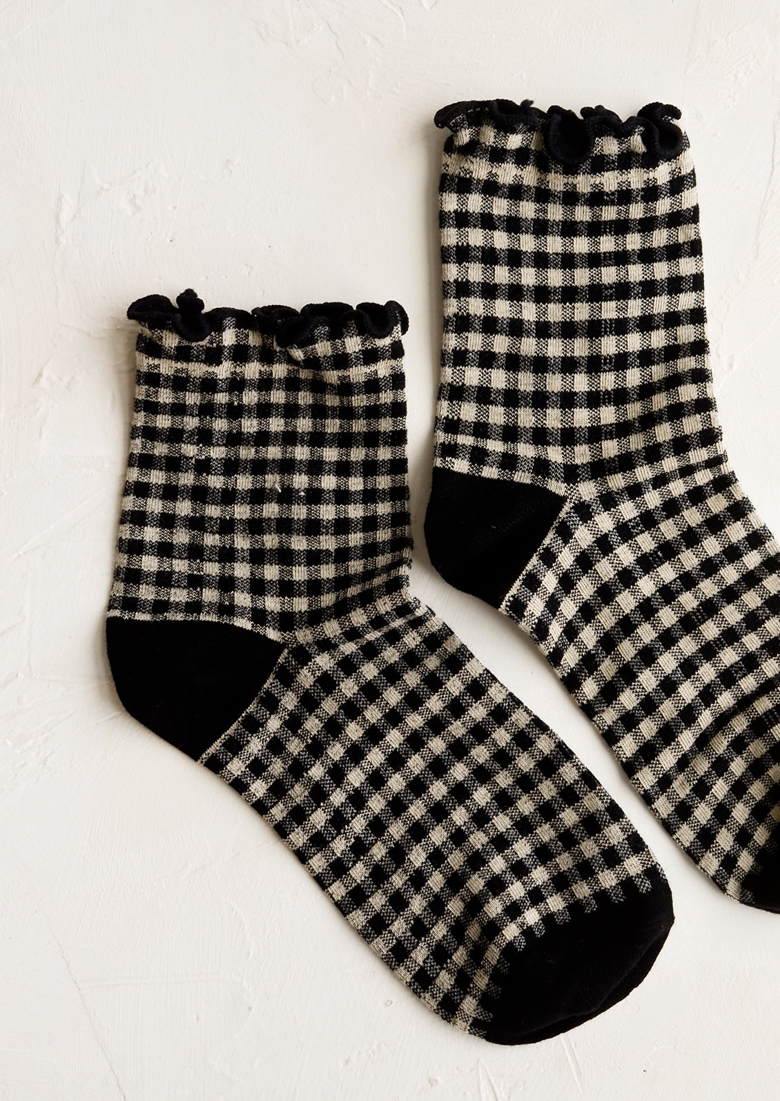 A pair of black gingham patterned socks with ankle ruffle.