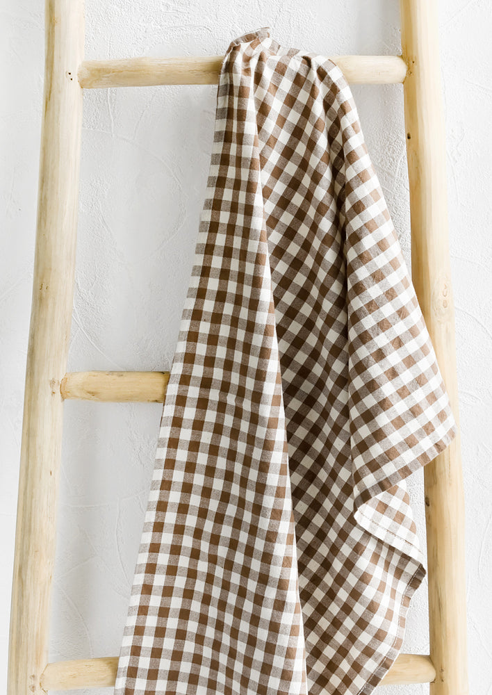 Cocoa: A gingham print tea towel in brown and white.