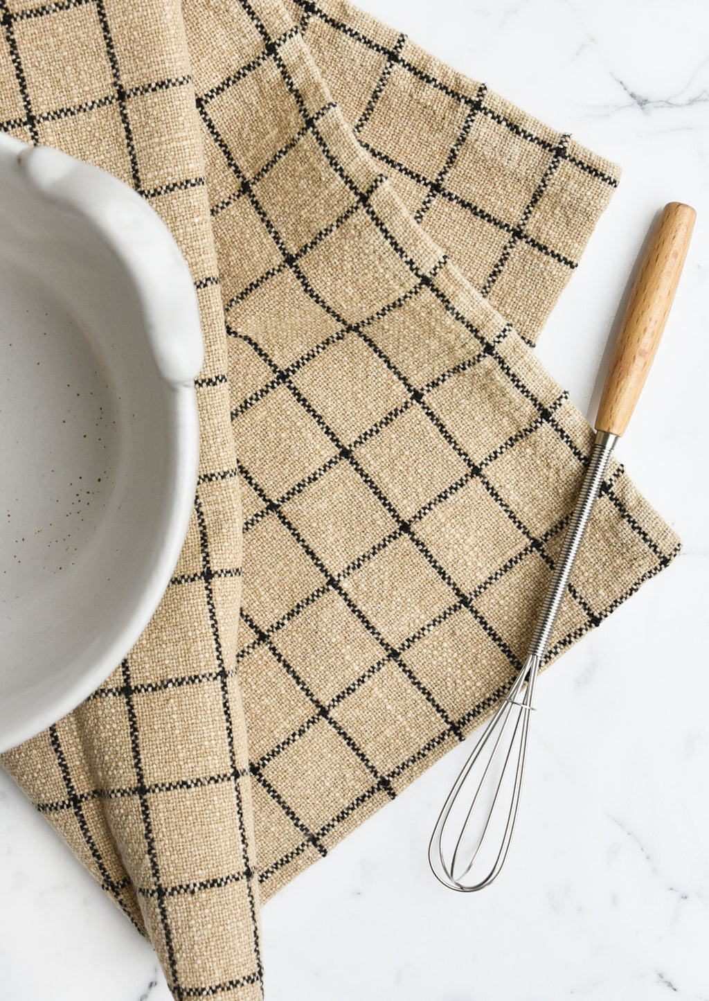 Sepia Check: A sepia toned tea towel with black grid pattern folded under a bowl with a whisk