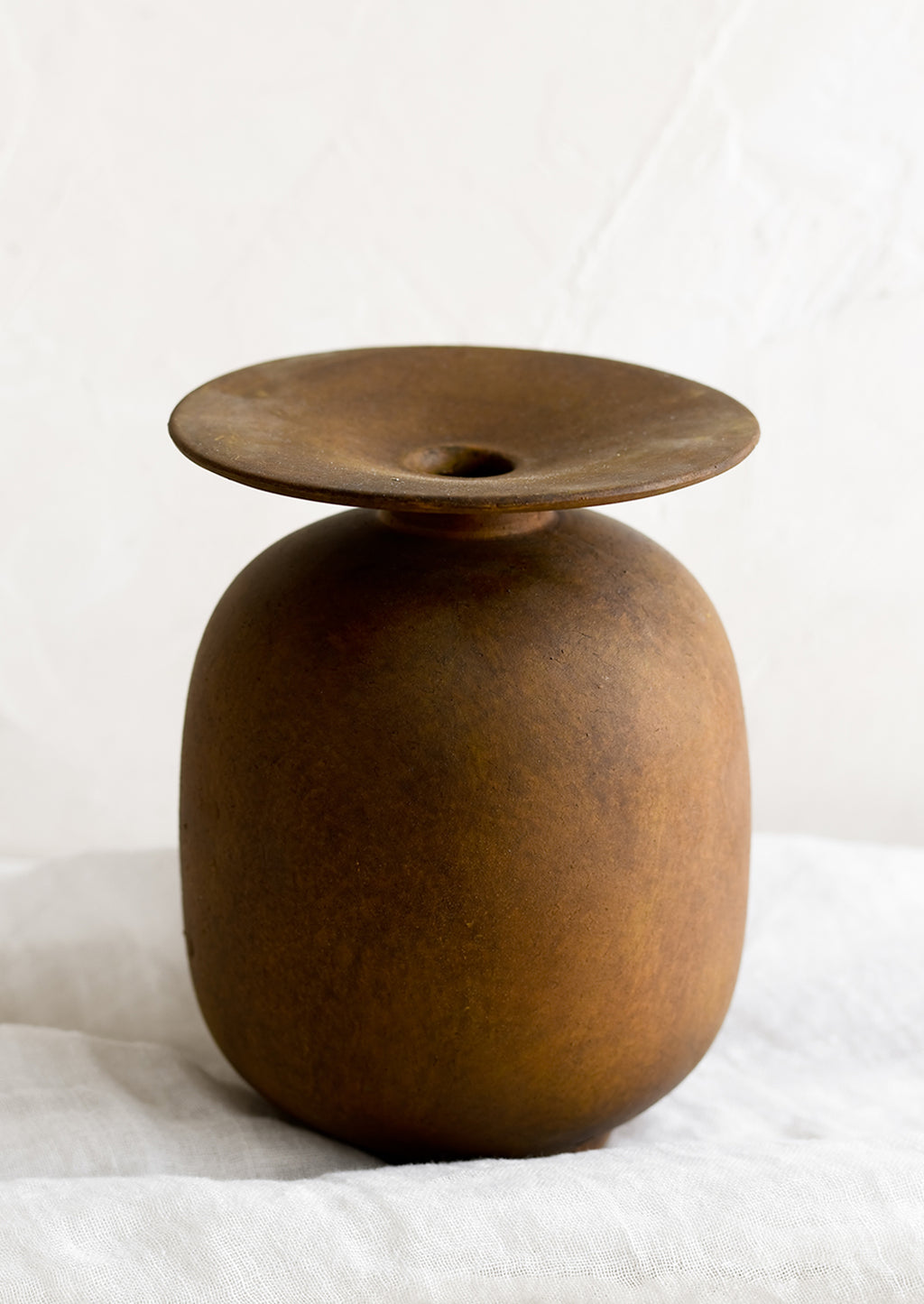 1: A brown distressed ceramic vase with saucer-like top.
