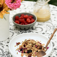 3: A ceramic bowl with yogurt and granola and wooden spoon.