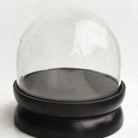1: A wide, round glass cloche with a black wooden base