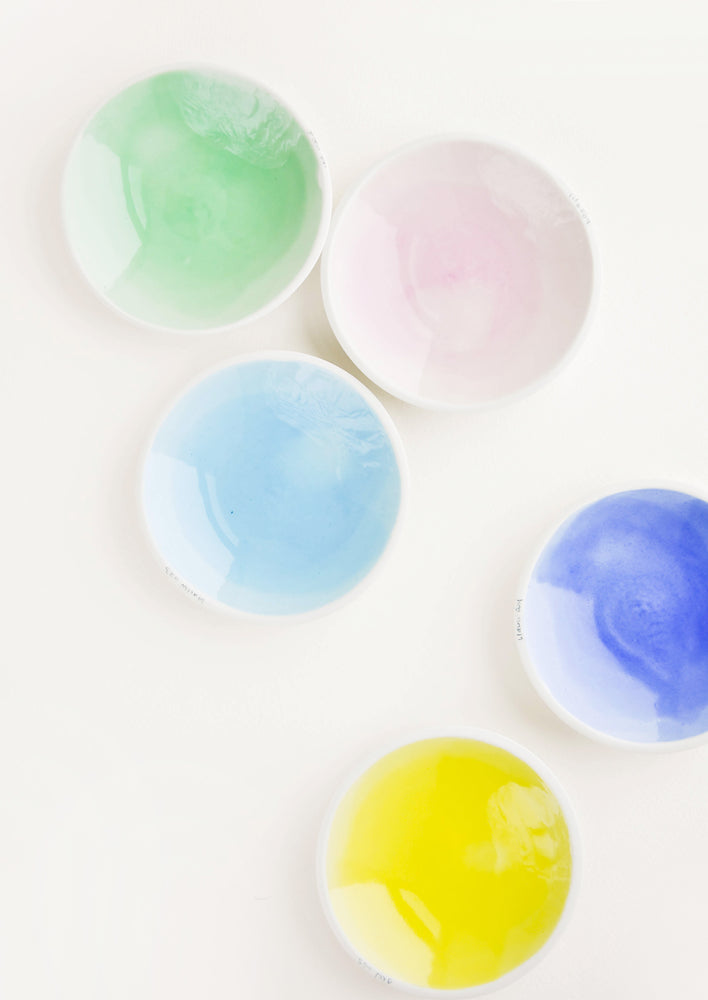 Small: Five shallow porcelain dishes in light blue, blue, pale pink, green, and yellow with shiny finishes and matte white rims.