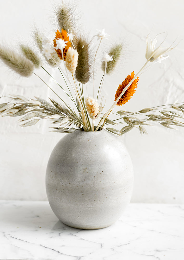 1: A ceramic bud vase with dried flowers.