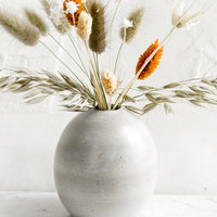 1: A ceramic bud vase with dried flowers.