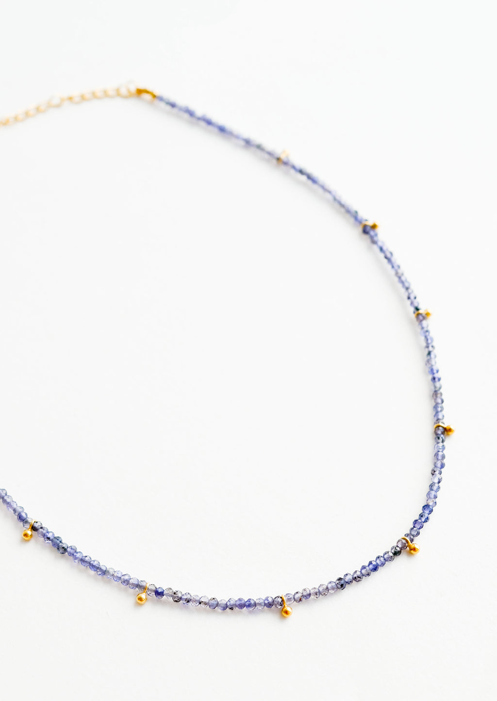 Iolite: A necklace of deep blue stones with evenly spaced gold beads and a golden chain clasp.