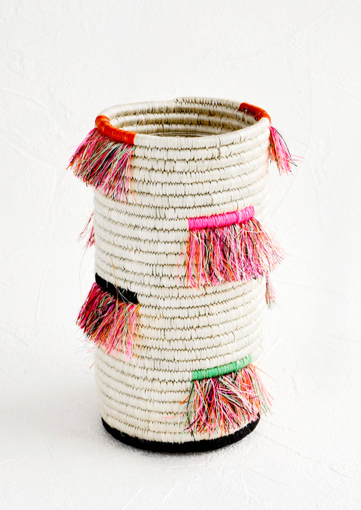 1: Tall cylindrical vase made from white woven sweetgrass with neon fringe throughout.