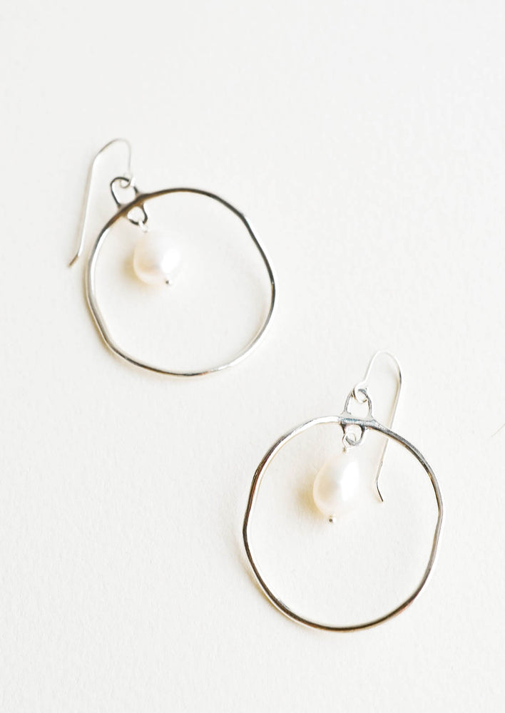 Circular drop earrings in silver with a small pearl dangling within.
