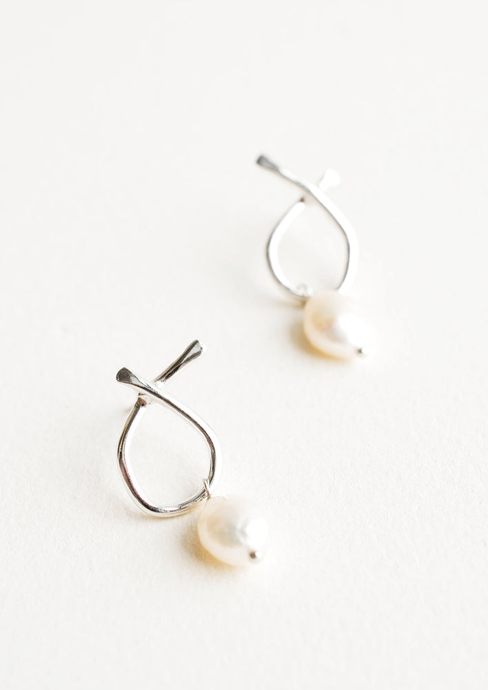 Pair of silver earrings featuring a slim asymmetrical frame on a post back and dangling pearl.