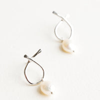 Sterling Silver: Pair of silver earrings featuring a slim asymmetrical frame on a post back and dangling pearl.