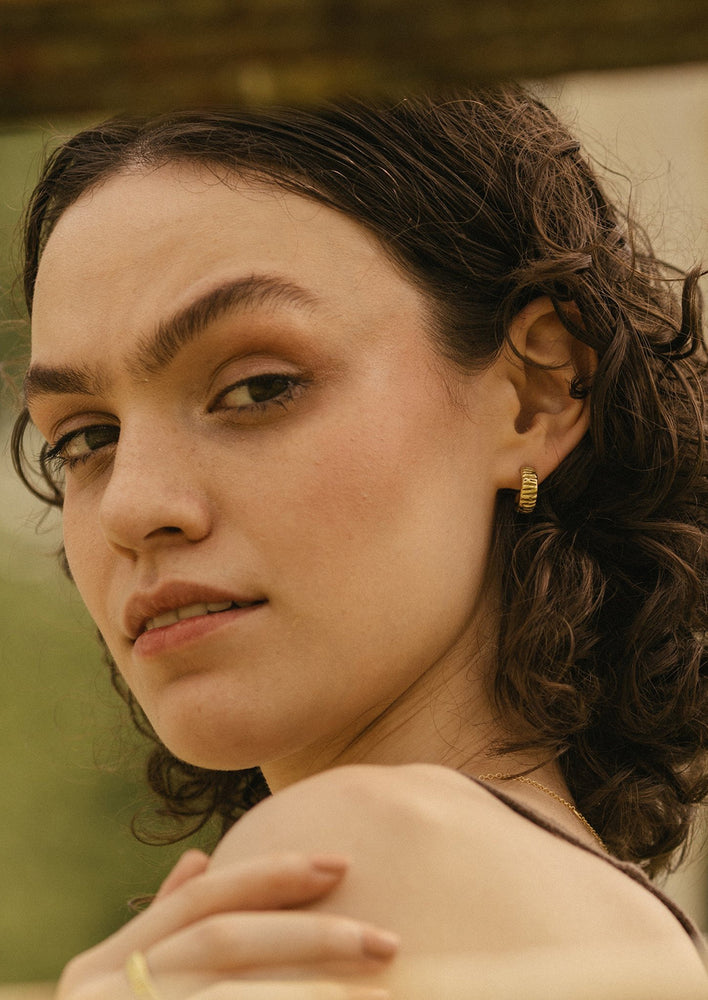 A woman wearing brass earrings.