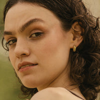 2: A woman wearing brass earrings.