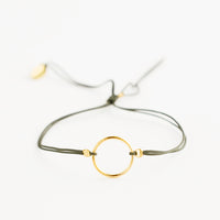 Khaki: Bracelet with yellow gold circle charm centered on an adjustable green string.