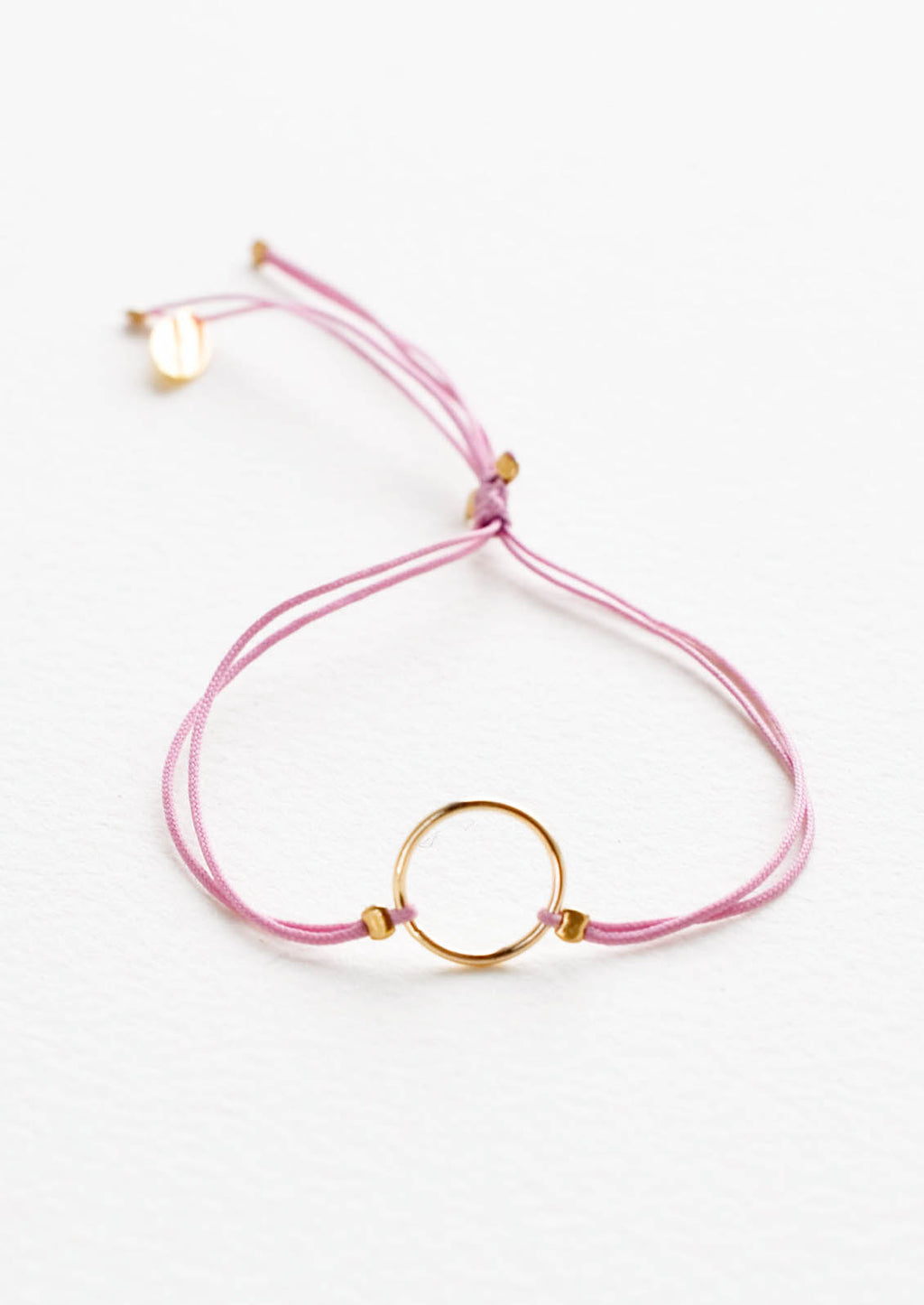 Orchid: Bracelet with yellow gold circle charm centered on an adjustable purple string.