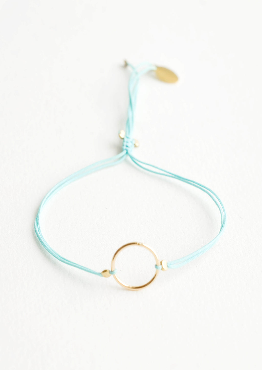 Aqua: Bracelet with yellow gold circle charm centered on an adjustable aqua string.