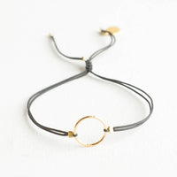 Charcoal: Bracelet with yellow gold circle charm centered on an adjustable dark grey string.