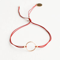 Crimson: Bracelet with yellow gold circle charm centered on an adjustable dark red string.