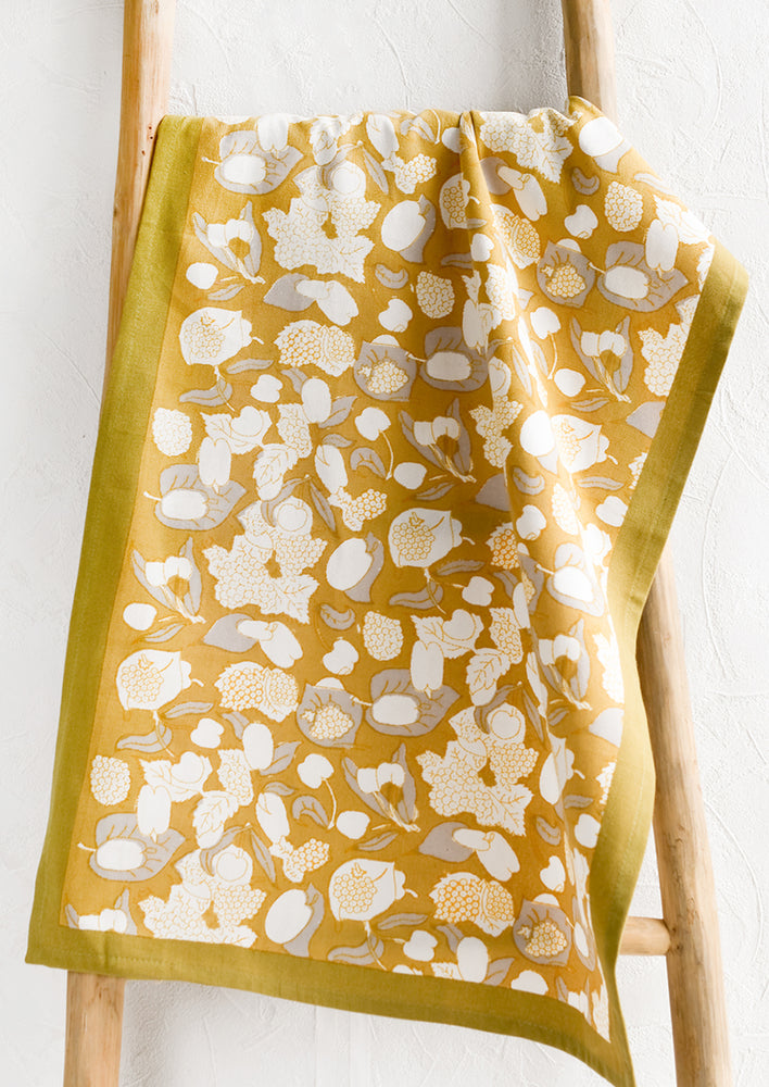 1: A gold, grey and white fruit print tea towel.