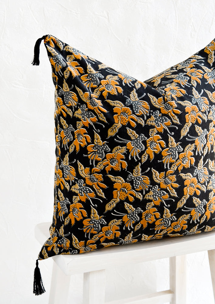 A square throw pillow in dark indigo with mustard floral print.