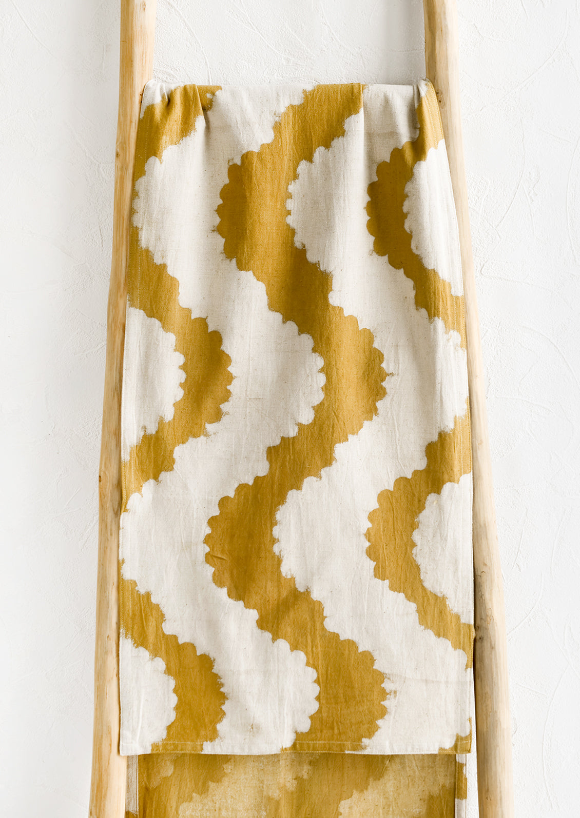 A mustard table runner with wavy pattern.