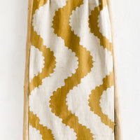 1: A mustard table runner with wavy pattern.