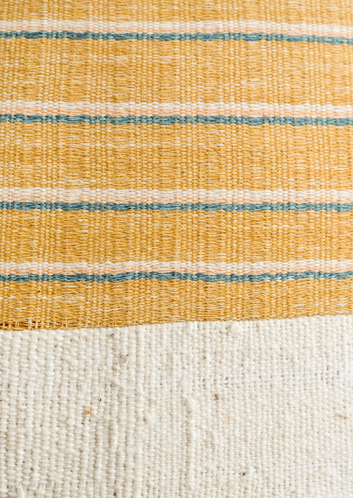 A mustard, ivory, peach and turquoise striped fabric combined with natural mudcloth fabric.
