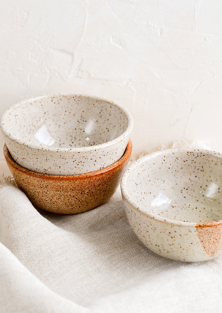 A stack of three small speckled ceramic bowls.