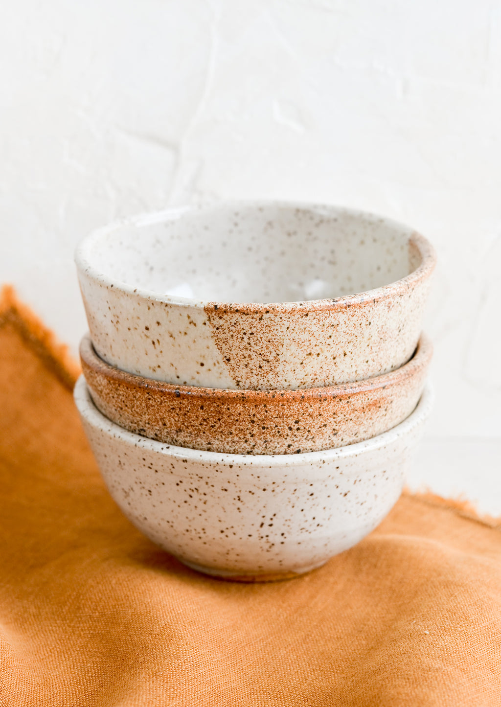 1: A stack of three small speckled ceramic bowls.