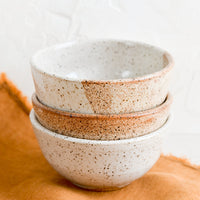 1: A stack of three small speckled ceramic bowls.