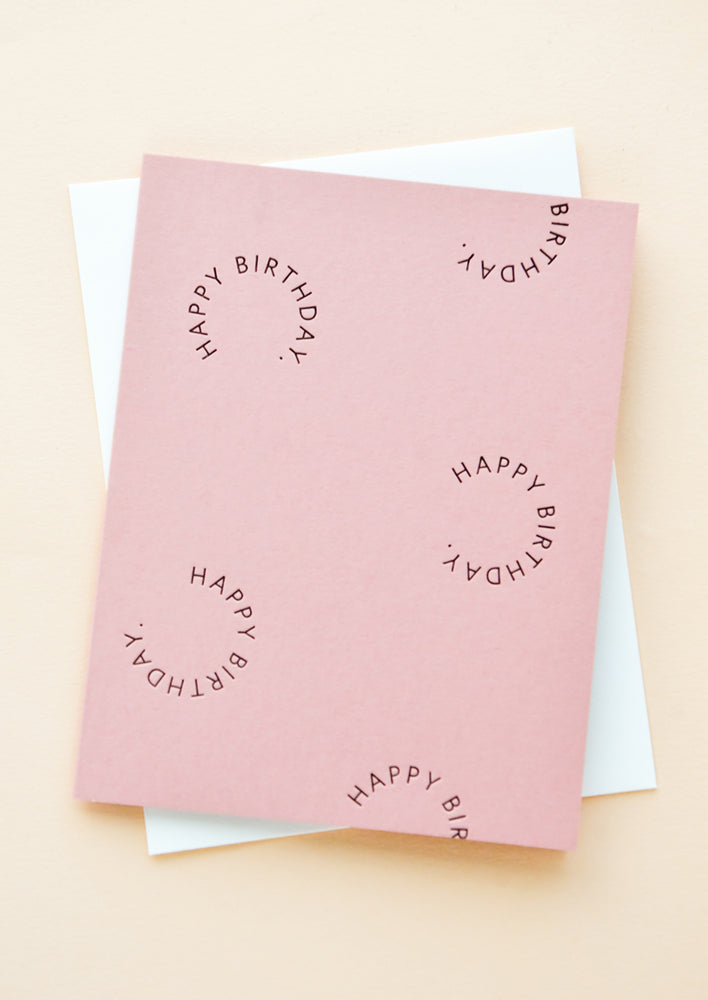 1: Pink notecard with the text "Happy birthday" set in a circle several times, with white envelope.