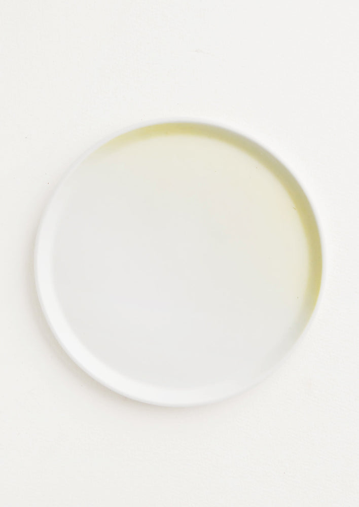 A rimmed white and yellow ombre porcelain plate.