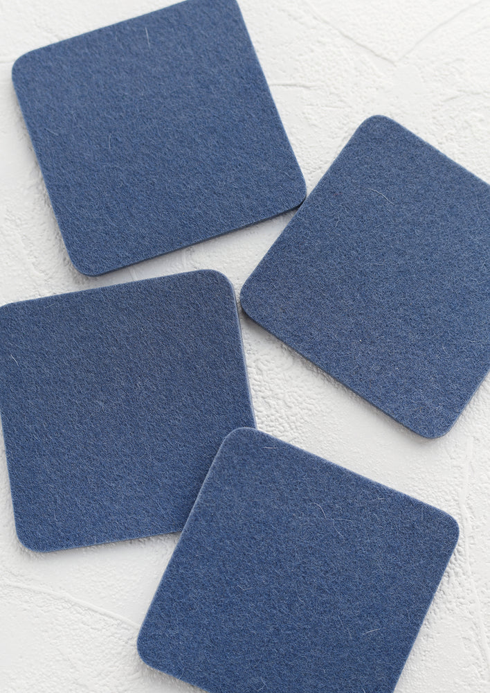 A set of four square merino wool coasters in storm blue.