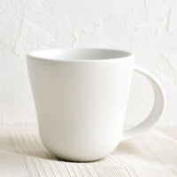 1: A matte white ceramic mug with softly curved shape.