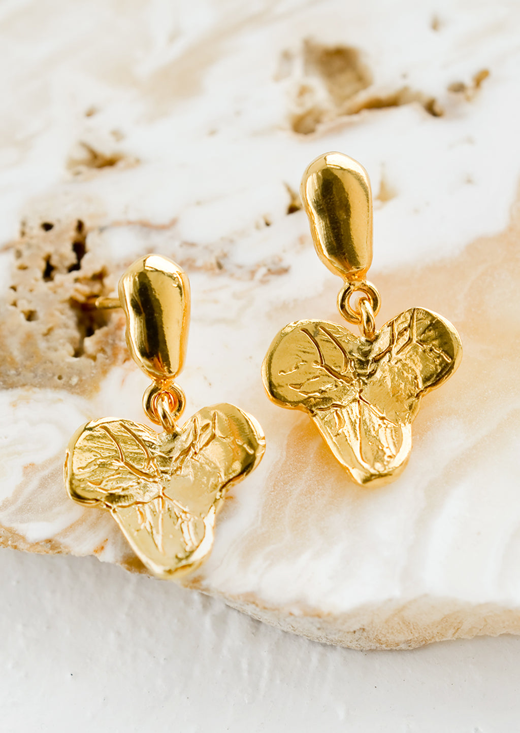 2: A pair of gold post back earrings in grape leaf shape.
