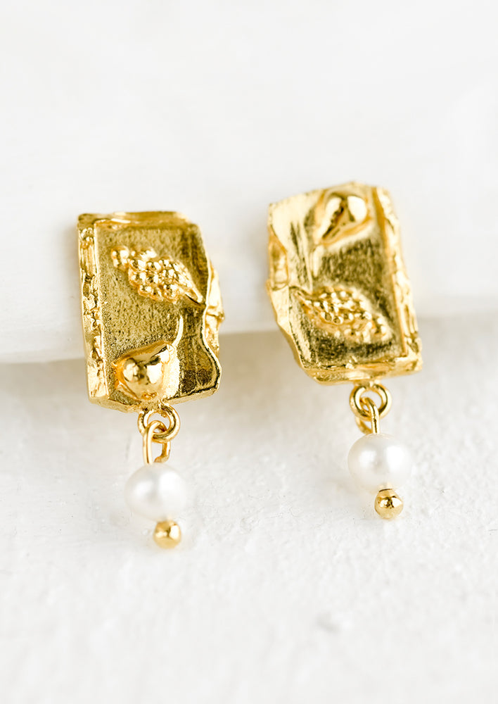 A pair of gold earrings in shape of broken tile with pearl detail.