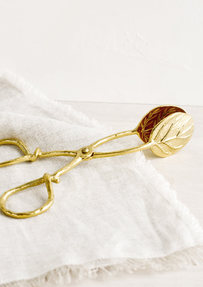 A pair of brass scissor-style serving tongs in leaf design.