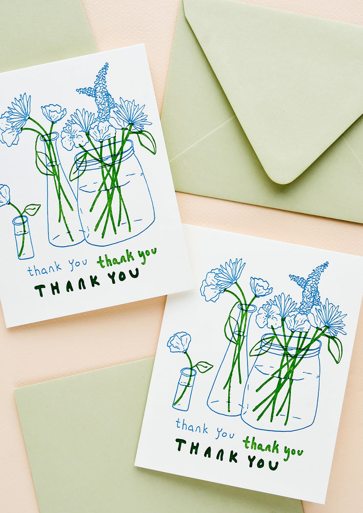 Two matching greeting cards with image of flowers in vases and "thank you" written three times, plus green envelopes.